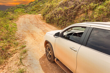 Obraz premium SUV car going up the sierra on a rocky road, white car on sloping ground during sunset. Concept of eco tourism 4x4 adventure. Brazilian sierra of the Minas Gerais state.