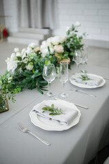 serving on the table of the newlyweds. White plate with glasses and utensils on the background of a blue tablecloth