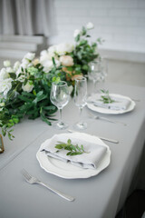 serving on the table of the newlyweds. White plate with glasses and utensils on the background of a blue tablecloth