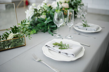 serving on the table of the newlyweds. White plate with glasses and utensils on the background of a blue tablecloth