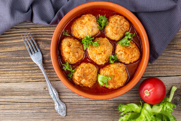 Meatballs in tomato sauce in a bowl on wooden table.