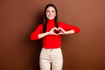 Portrait of attractive cheerful girl showing heart sign shape amour isolated over dark brown color background