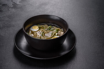 Fresh delicious hot soup with noodles and quail egg in a black plate