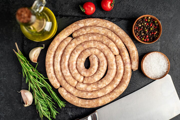 raw spiral chicken sausages with ingredients on stone background