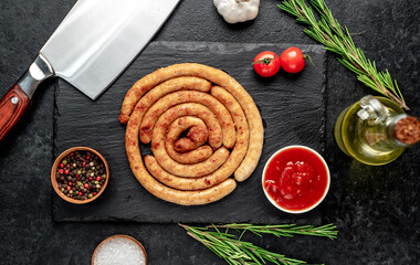 grilled chicken sausages in spiral shape with ingredients on stone background