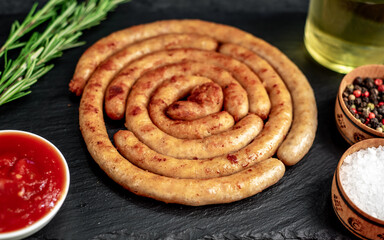 grilled chicken sausages in spiral shape with ingredients on stone background