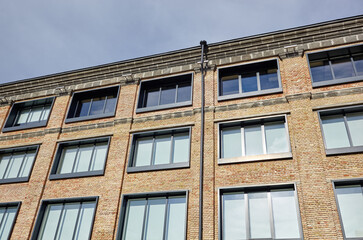 Fototapeta premium Brick building with windows and downspout against blue sky