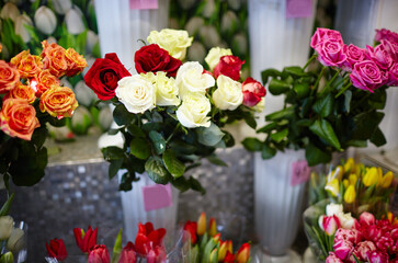 Blurred image of bouquet of fresh roses and tulips in flower shop. Lot of multicolored roses and tulips bouquets