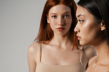 Multiracial young two women posing while looking at camera and aside