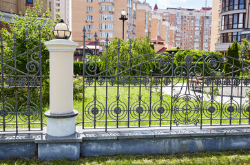 Wrought iron fence. Image of a Beautiful decorative cast iron wrought fence with artistic forging and stone columns