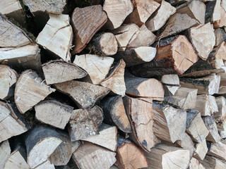 Closeup photograph of neatly stacked firewood, mostly quarter logs. The wood is from various species, mostly beech and oak.
