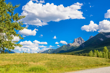 Scenery of high mountain peak over blue sky with white clouds.