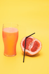 Fresh orange smoothie with a grapefruit or orange tube, ripe fresh orange on a yellow background, prepare fresh orange juice and smoothies, top view with place for text.