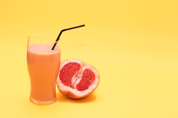 Fresh orange smoothie with a grapefruit or orange tube, ripe fresh orange on a yellow background, prepare fresh orange juice and smoothies, top view with place for text.