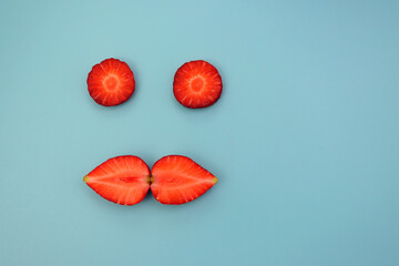 Red ripe strawberries, split into two halves on a blue background. Strawberry circles and halves.