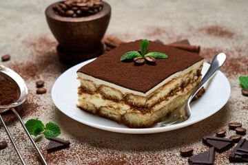 Portion of Traditional Italian Tiramisu dessert on grey concrete background