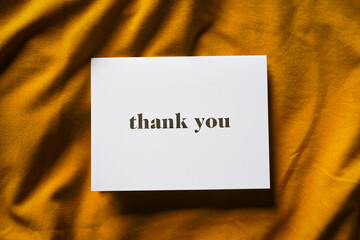 Thank you card on yellow fabric background. Elegant feminine composition. Special thank you note.