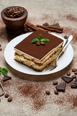 Portion of Traditional Italian Tiramisu dessert on grey concrete background