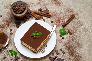 Portion of Traditional Italian Tiramisu dessert on grey concrete background