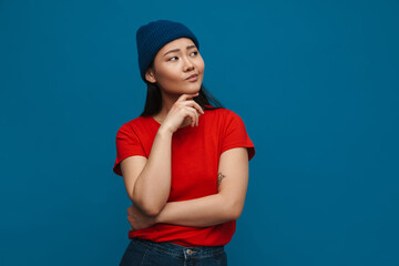 Asian teen girl in hat thinking and looking aside