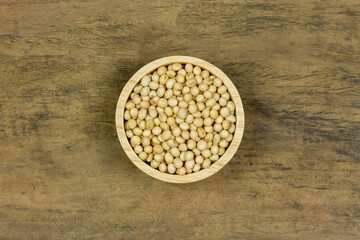 Soybeans in wooden bowl on wooden table, top view. Soy has health benefits because high protein and many other nutrients.
