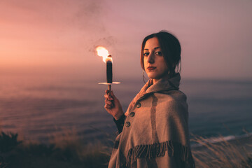 Close-up of girl with torch and poncho at susnet