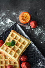 Tasteful Belgian waffles and dried strawberries for breakfast, with sugar powder and syrup