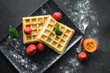 Tasteful Belgian waffles and dried strawberries for breakfast, with sugar powder and syrup