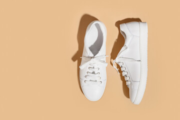 White female gumshoes on beige background with copy space. View from above. Copy space.