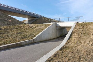Empty overpass for cars and underpass for cyclists and pedestrians under a blue sky in early spring.