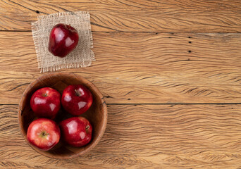 Red apples in a bowl over wooden table with copy space