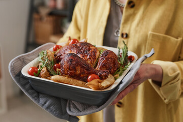 Close-up of senior woman holding dish with roasted chicken and vegetables © AnnaStills