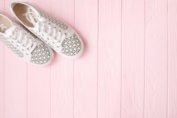 White sneakers on light pink background. Women's shoes. stylish white sneakers.