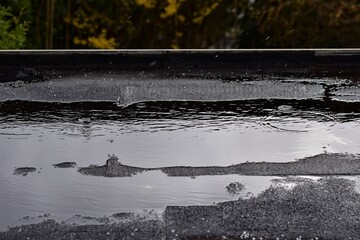 Light rain on a black flat roof against a green background