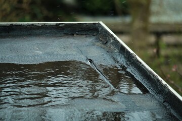 Light rain on a black flat roof with a small leak