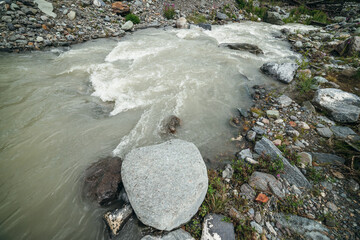 Minimalist mountain scenery with rapids of fast turbulent river. Beautiful mountain landscape with powerful mountain creek with stones and boulders. Minimal scenic nature background of mountain river.