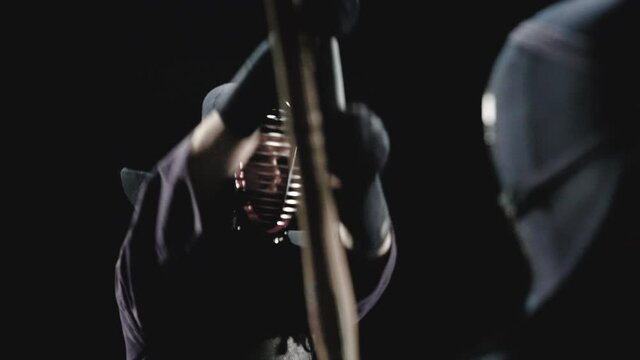 Japanese kendo fighters with bamboo swords on a black background. Slow motion