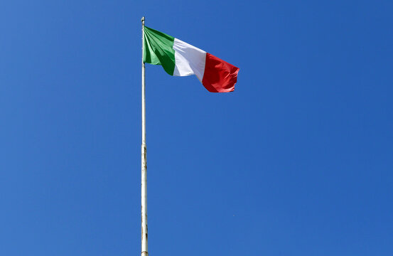 bandiera italiana che sventola sull'asta contro il cielo azzurro