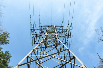 High-voltage tower under a blue sky. Bottom view of the tall high-voltage tower