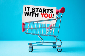 a business card with text IT STARTS WITH YOU in a shopping cart. business and finance