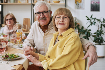 Fototapeta na wymiar Portrait of happy senior couple smiling at camera sitting at dining table during dinner at home