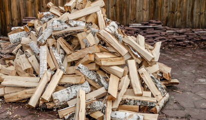 Birch logs in the form of firewood in a pile in the yard.