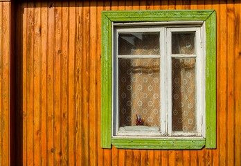 The wall of a wooden house with one window.