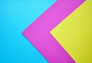 Multicolored paper, paper background. Colored paper in blue, pink and yellow.