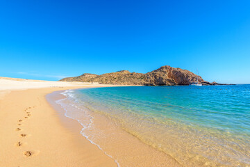 Footprints on the beautiful ocean sand. Set of pictures showing ocean waves in different stages over footprints. Cabo San Lucas. Mexico.