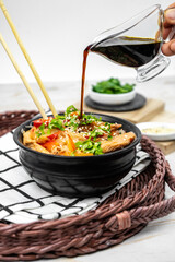 Asian salad with rice noodles, vegetables, mushrooms, chicken and soy sauce. Funchose with white transparent noodles in black plate