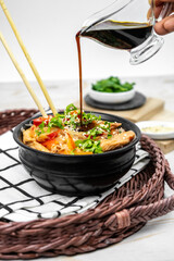 Asian salad with rice noodles, vegetables, mushrooms, chicken and soy sauce. Funchose with white transparent noodles in black plate
