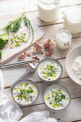Traditional summer cold soup of homemade yogurt, cucumbers and fresh herbs on a table