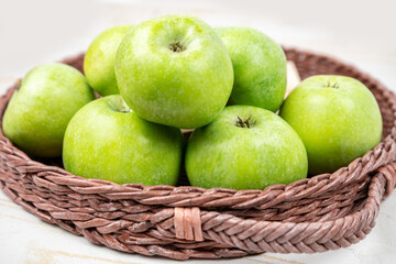 Group of ripe green apples in a basket on white background