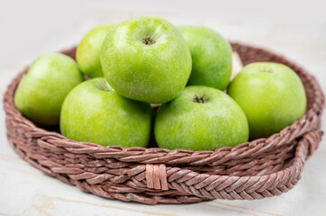 Group of ripe green apples in a basket on white background
